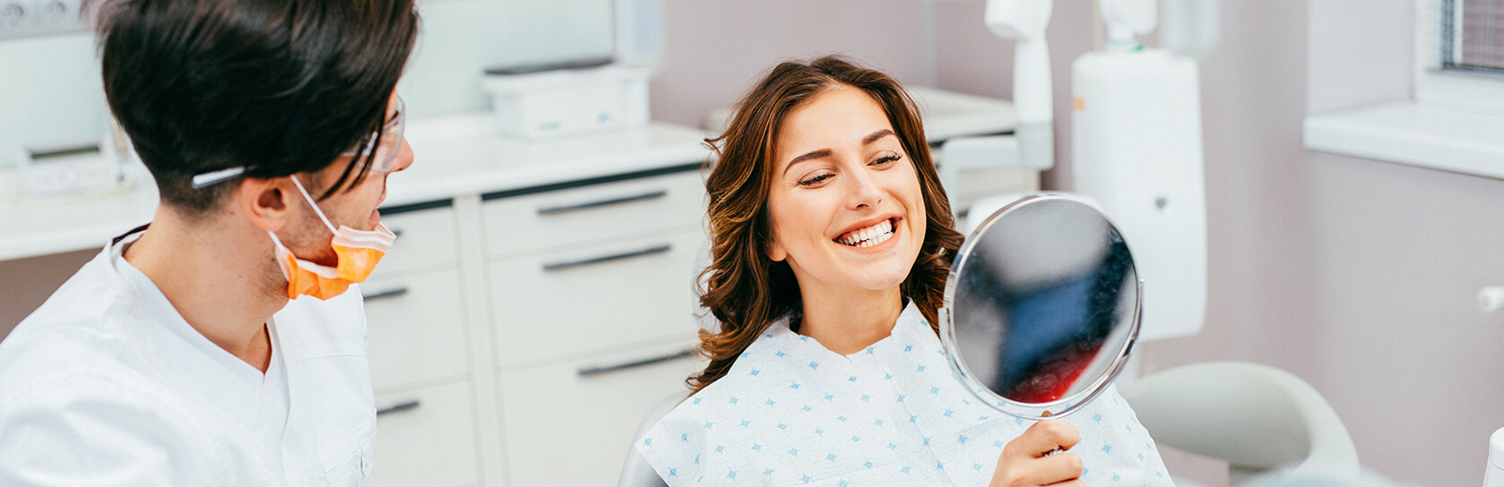 woman examining her smile in a mirror