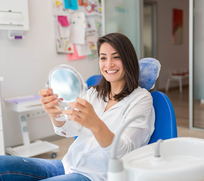 woman examining her smile in a mirror